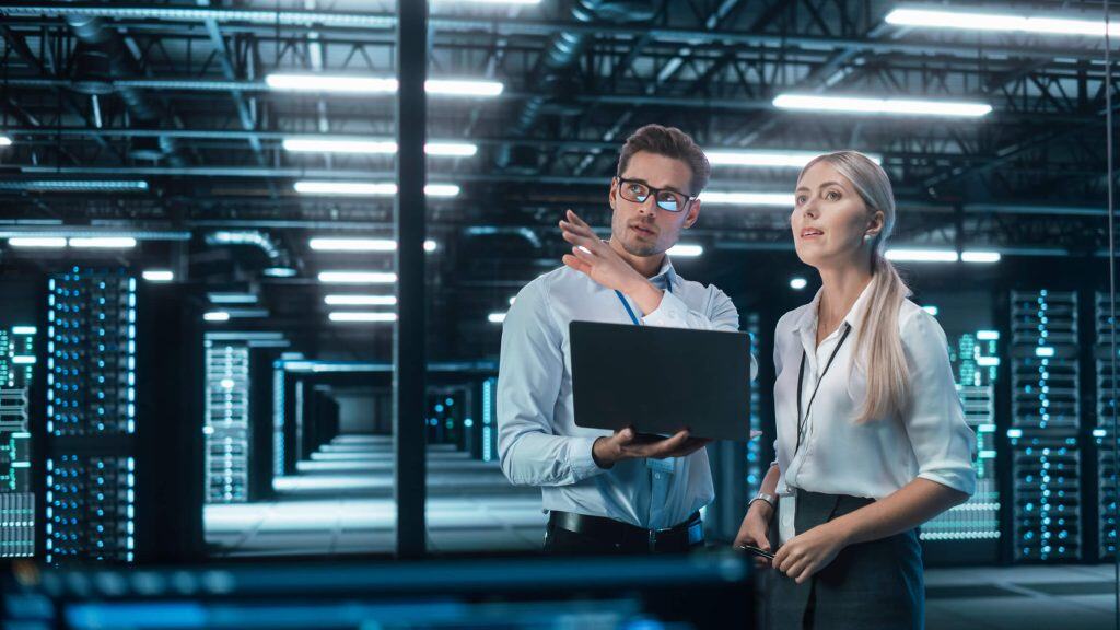 Ein Mann und eine Frau stehen im Serverraum eines Webhosting Anbieters